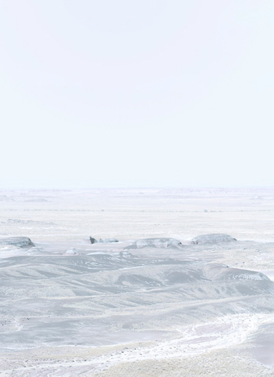 Minimalist coastal landscape with layered horizons of pale gray and white tones. Rocky outcroppings and sandy beach dissolve into misty atmosphere, creating a subtle, almost monochromatic composition that emphasizes atmospheric depth and geometric abstraction.
