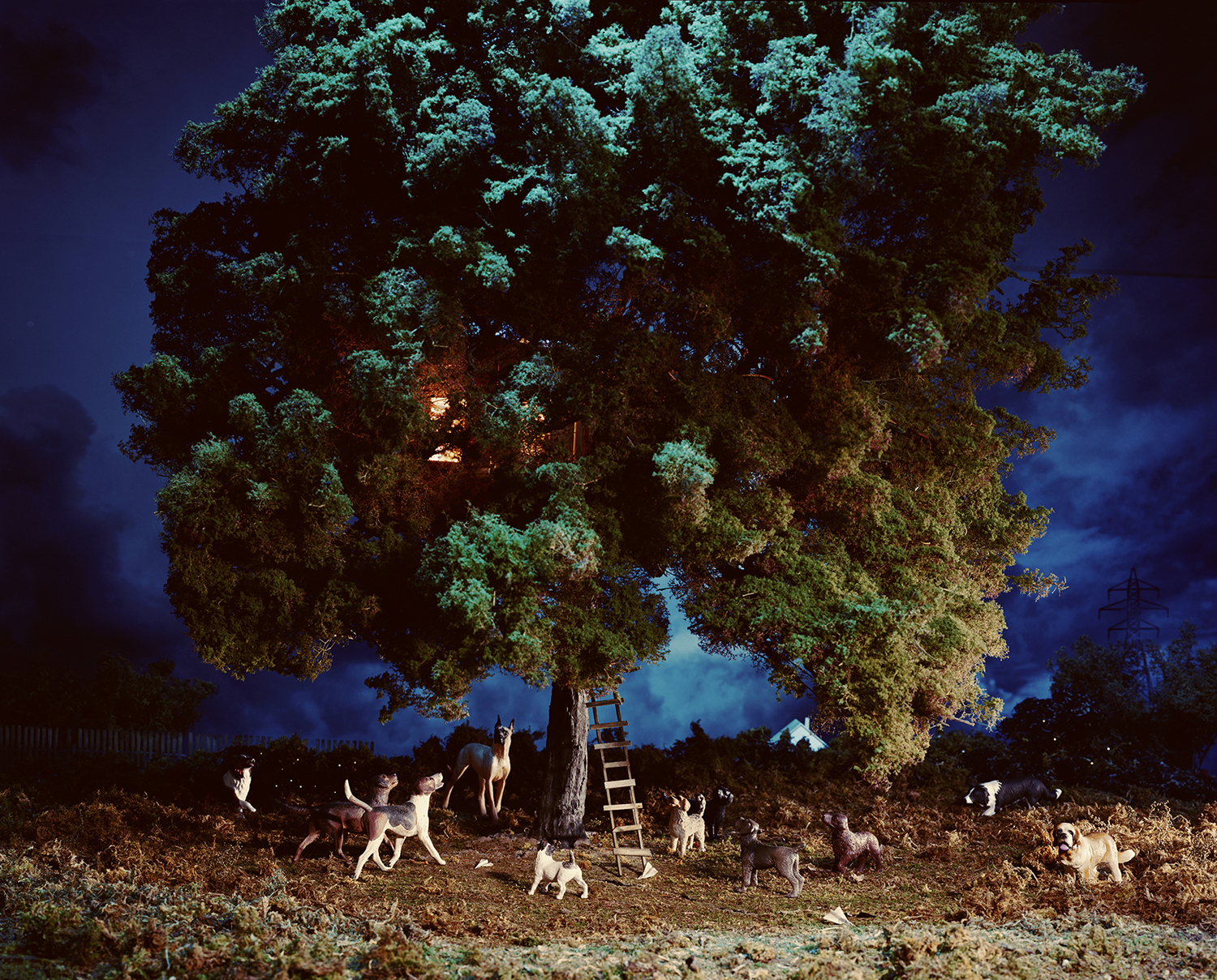 A massive, luminously lit tree with turquoise-tinted foliage dominates a twilight landscape, surrounded by numerous goats of varying sizes gathered at its base near a wooden ladder. The surreal, dreamlike composition features a deep blue evening sky and distant structures on the horizon, creating an otherworldly scene that blends naturalistic detail with imaginative staging.