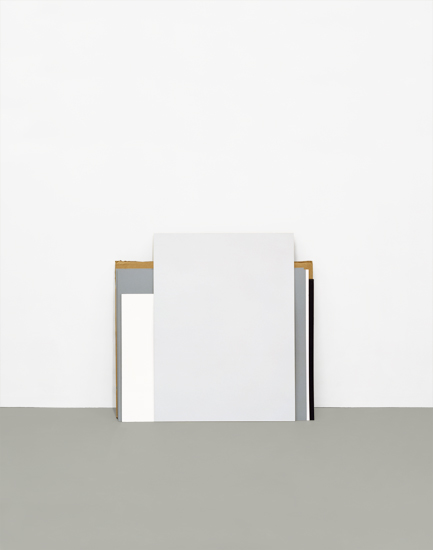 A minimalist composition featuring a large white rectangular form positioned against a gray-beige ground, with geometric brown and dark metal-like elements flanking its sides, creating a stark architectural study in neutral tones.
