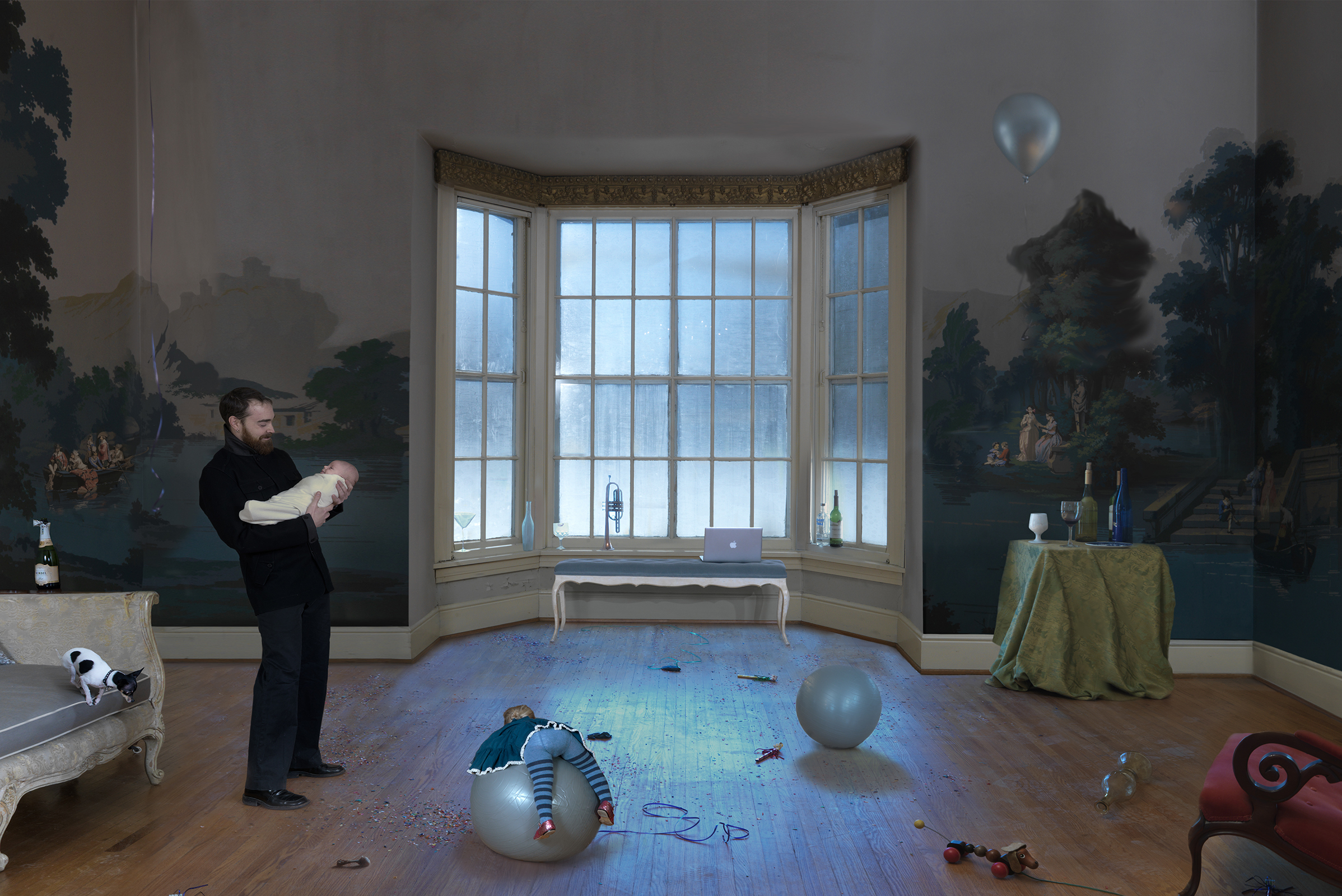 A man in dark clothing stands in an elegant room holding an infant, surrounded by children's toys and exercise balls scattered across a blue floor. Classical landscape murals cover the walls behind ornate bay windows overlooking a snowy landscape, while furniture, plants, and various household items create a sense of domestic chaos within the refined architectural space.