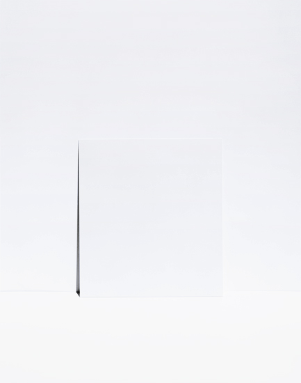 A minimalist composition featuring a single dark diagonal line extending from the lower left toward the upper center of a predominantly white field. The austere arrangement emphasizes negative space and subtle tonal variations across the pale background.