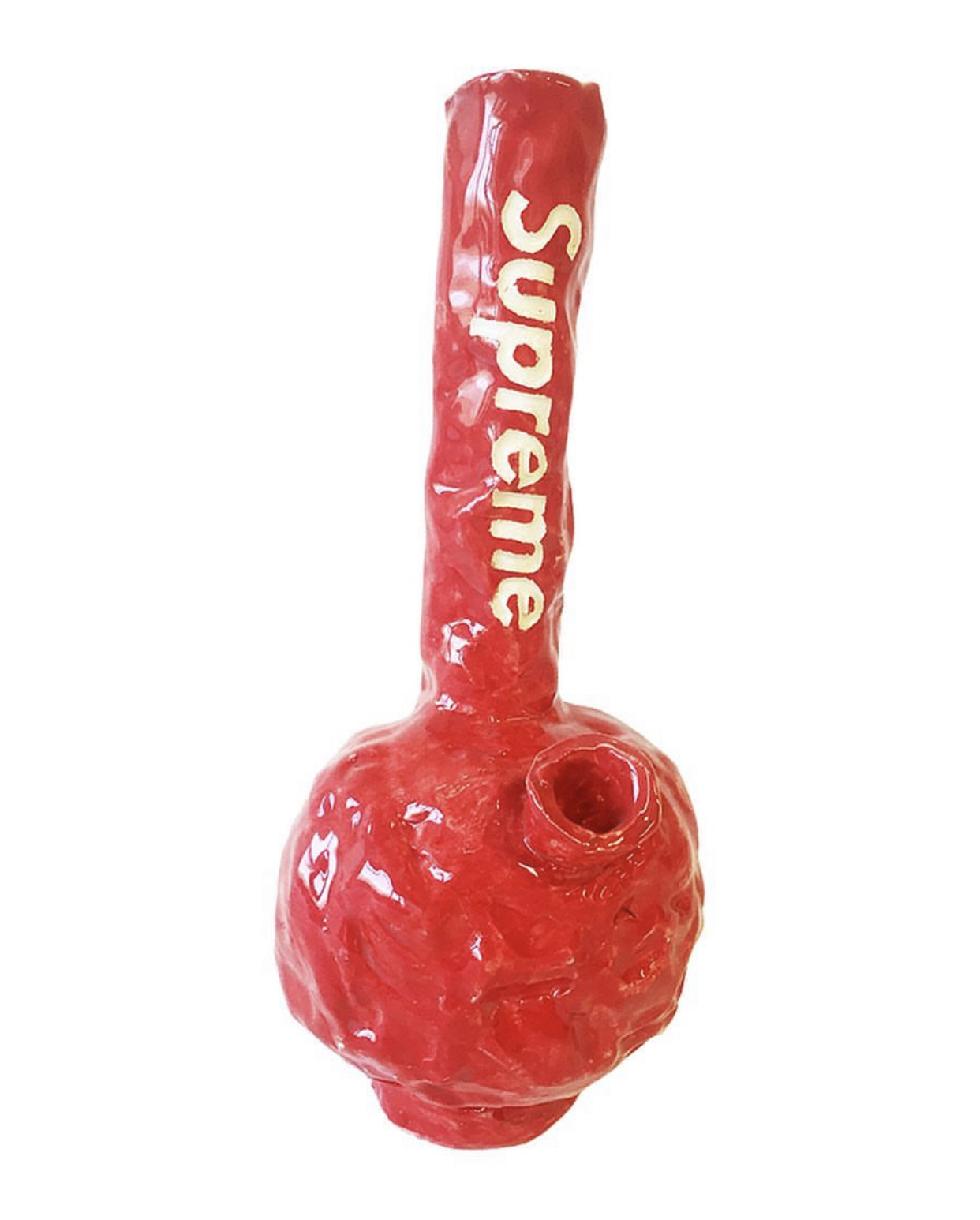 A bright red glazed ceramic vessel with a rounded bulbous base and tall cylindrical neck, featuring cream-colored text reading "supreme" along the stem. The glossy surface displays visible brush marks and an organic, handcrafted appearance.
