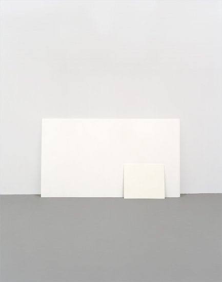 Minimalist composition featuring white rectangular forms arranged on a gray surface against a pale background, creating a study of geometric shapes, subtle shadows, and tonal variation.