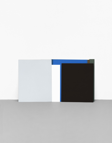 Abstract composition featuring geometric forms in muted tones—a light gray-blue rectangular shape on the left, a dark charcoal black square on the right, connected by a horizontal blue bar, all positioned against a gray ground plane. The minimalist arrangement emphasizes color relationships and spatial positioning.