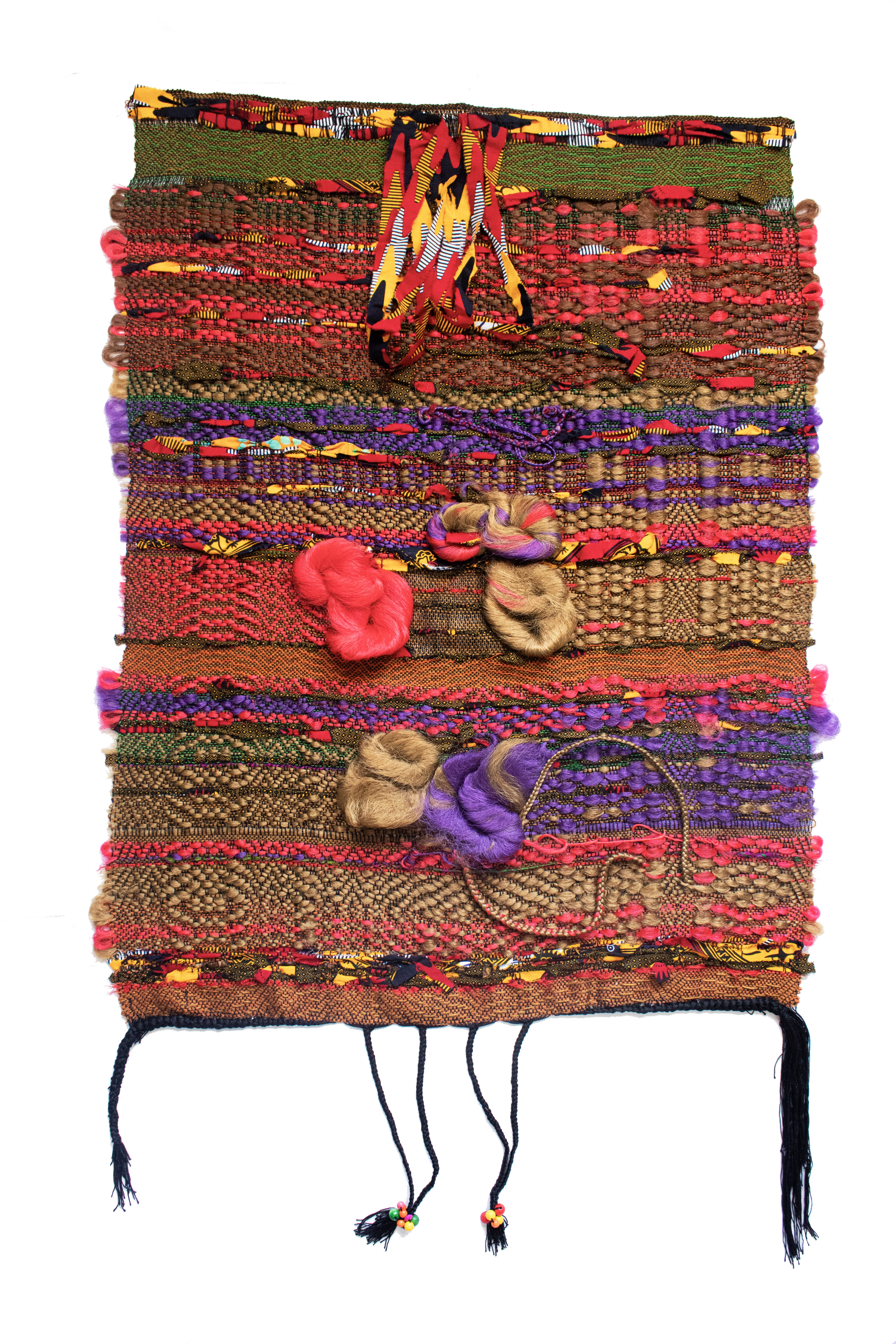Vertically stacked horizontal bands of richly textured woven fabrics in warm earth tones, vibrant reds, purples, and golds, interspersed with three-dimensional sculptural forms in coral, tan, and purple. Two dark braided cords with beaded ends hang from the bottom of the composition. The layered arrangement combines various textile patterns and materials to create a dense, tactile mixed-media work.
