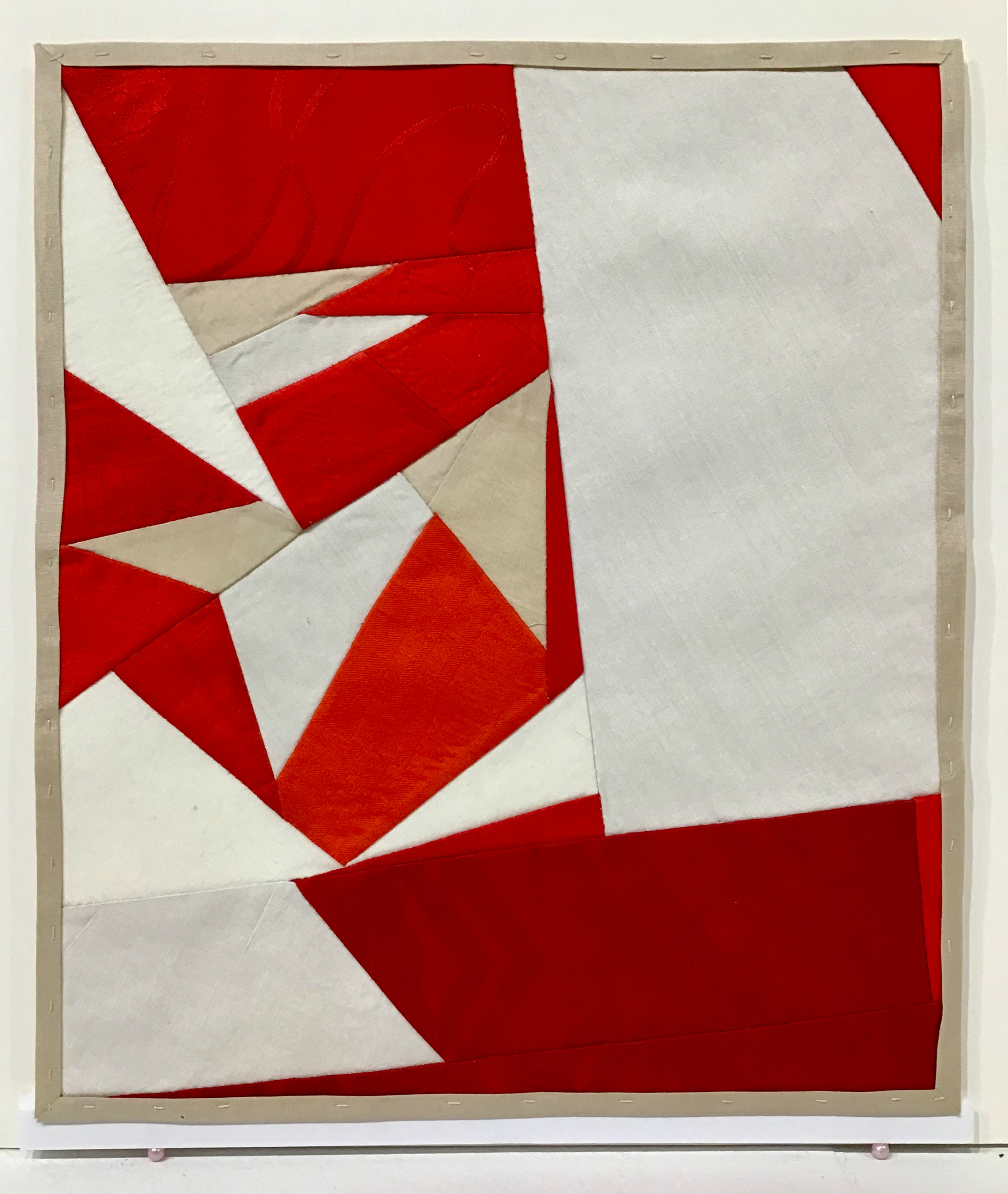 Abstract composition of interlocking geometric shapes in red, cream, and white tones, created from pieced vintage silk segments arranged within a neutral linen frame.