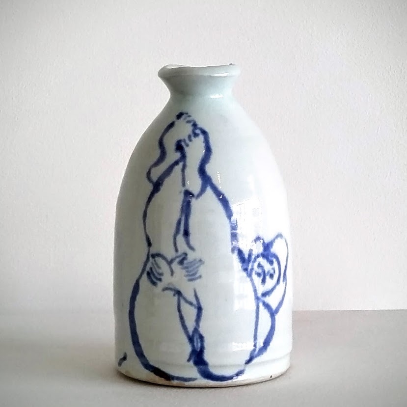 White porcelain bottle with a narrow neck and bulbous body, decorated with loose cobalt blue line drawings of abstracted human figures in dynamic poses across its surface.