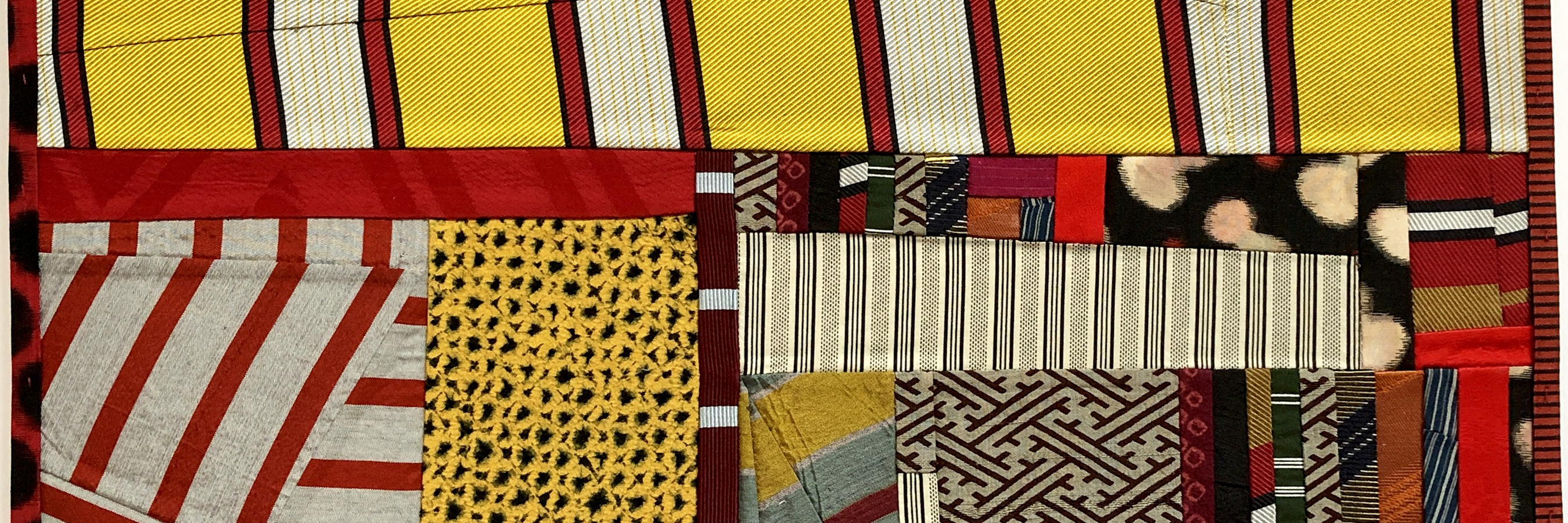 Layered textile collage composed of striped, patterned, and solid fabric pieces in red, yellow, cream, black, and earth tones, arranged in an abstract composition with visible stitching creating depth and texture throughout.