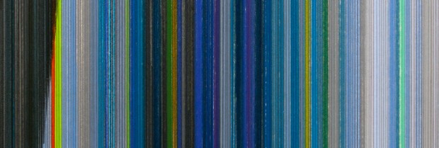 Vertical striped composition featuring thin, closely-spaced lines in varying shades of blue, gray, yellow, and teal, creating a rhythmic pattern that shifts subtly across the width of the work.