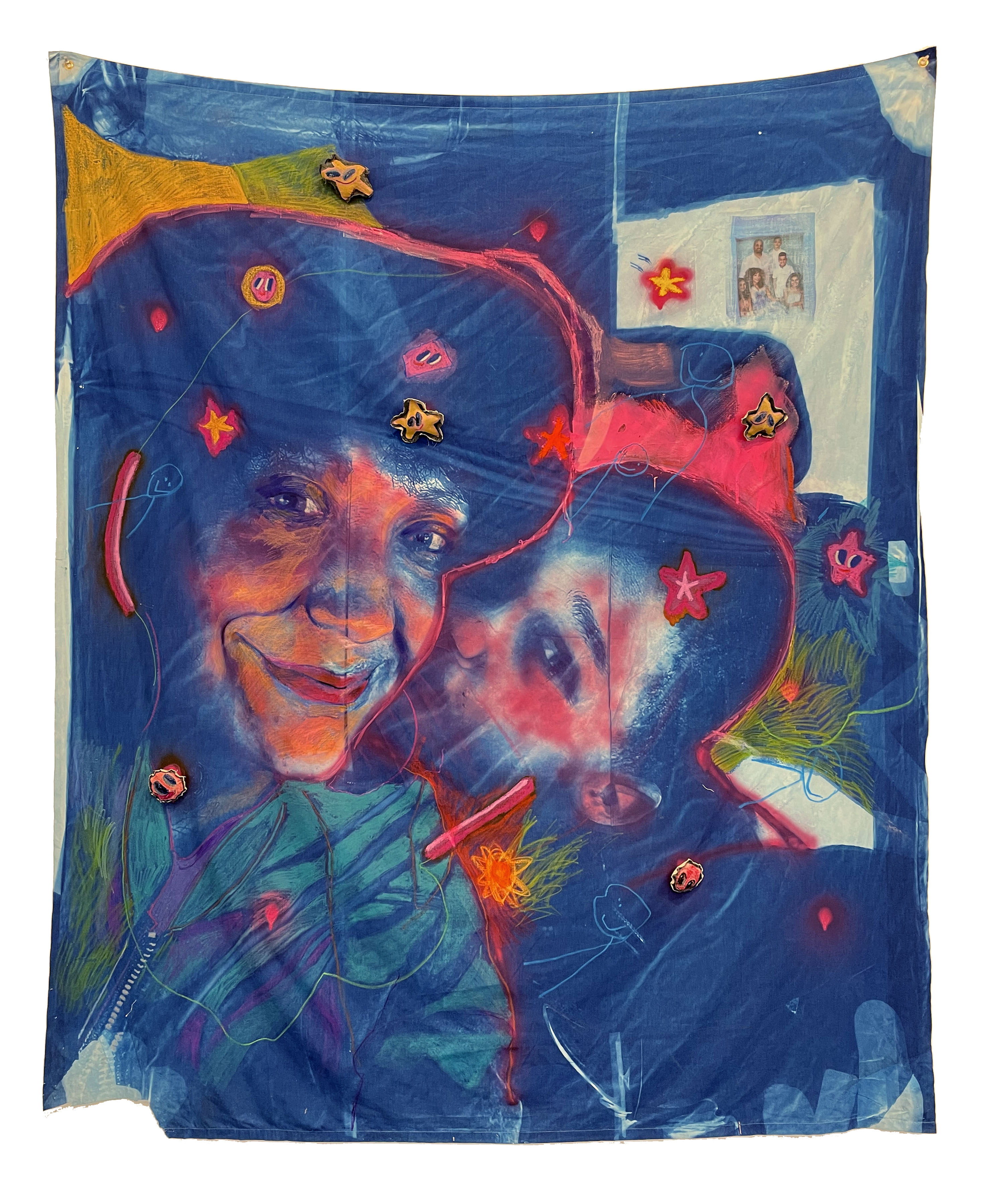 Mixed-media tapestry featuring expressive portraits of two figures rendered in warm orange and red tones against a deep blue background, embellished with fabric appliqués including golden stars, red flowers, and green foliage elements, with a photograph pinned in the upper right corner.