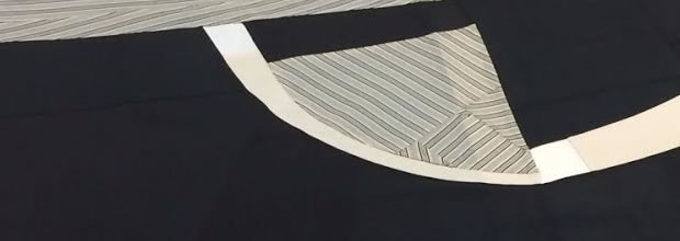 Abstract composition of layered black and cream fabrics with geometric curved and angular forms, featuring striped patterns and gestural seams that create a sense of movement and depth across the monochromatic surface.