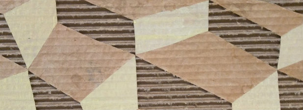 Geometric composition of triangular and rectangular shapes in cream, tan, and brown tones arranged across a textured striped background, combining weathered and new materials with visible edges and boundaries between contrasting surfaces.